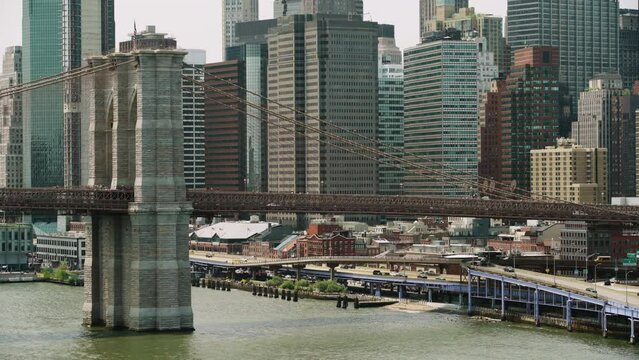 Brooklyn Bridge Tower Rising Up From River In NYC With Skyscrapers In Background