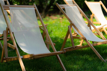 White wooden lounge chairs in a park in Milan, Italy.