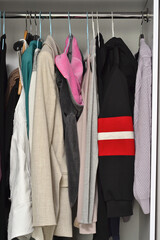 women's things hang on hangers in a light closet