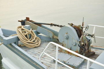 iron boat winch and anchor at ship prow in river on sunset