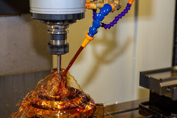Close up scene the CNC milling machine cutting the shell mold parts with oil coolant method .