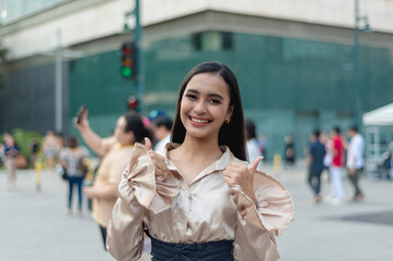 A pretty asian woman standing outside wearing a light tan silk blouse and a high waist skirt,...