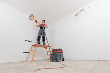 Painter work with white ceiling polishing and sanding surface after putty for painting