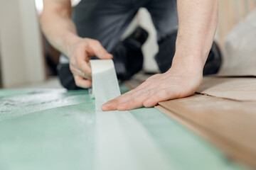 Professional builder use spreads underlayment for laying laminate flooring in white room