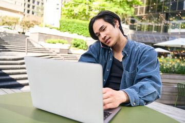 Busy confident asian man using laptop communication, having mobile phone call