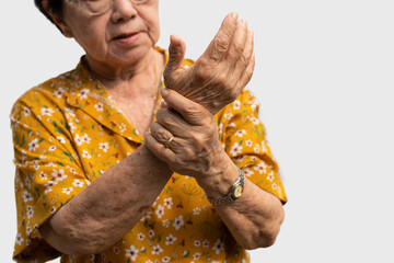 Elderly Asian woman patients suffer from numbing pain in hands from rheumatoid arthritis. Senior woman massage her hand with wrist pain. Concept of joint pain, rheumatoid arthritis, and hand problems.