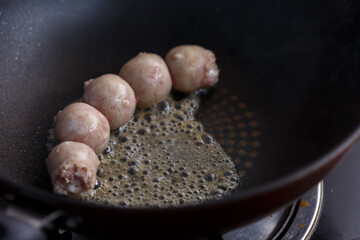 Homemade pork sausages fried in a pan.