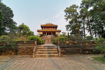 The scenery of Minh Lau pavilion inside the Emperor Minh Mang tomb in Hue city, Vietnam, surrounded by green trees.