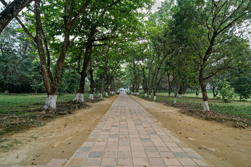 Obraz premium The scenery of the exit from the Emperor Minh Mang Tomb in Hue city, Vietnam, with beautiful green trees and grass that is nice and shady.