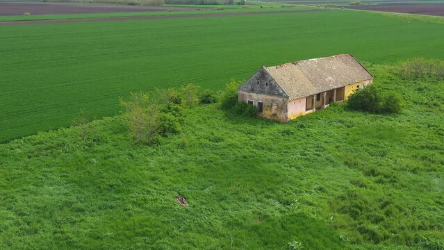 Old abandoned and ruined farm house surrounded with cultivated fields in Vojvodina from drone pov, aerial shot