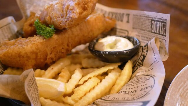 close up view to a plate of fish and chips with tartar sauce for dinner lunch meal, fried cryspy fish