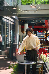 Vertical view of handsome asian man wearing stylish sweater looking at laptop