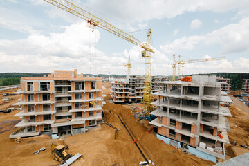 New construction site with cranes on blue sky with clouds background. Steel frame structure,...