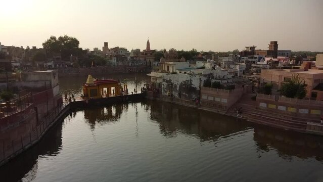 drone filming at sunset, sacred lake shyama kunda on govardhan hill in india, place of pilgrimage, holy place
