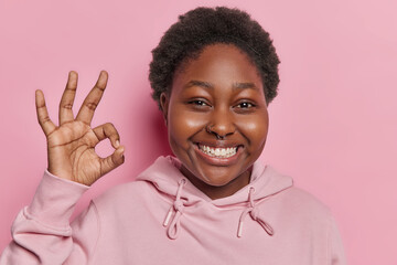 Agreement and affirmation concept. Assured dark skinned woman look confidently makes okay gesture...