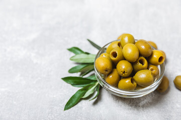 Green olives in a bowl with leaves on a textured blue backdrop. Delicious and healthy food. Delicacy.Mediterranean Kitchen. Close-up. Place for text. copyspace.