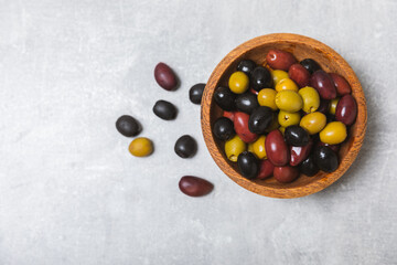 Set of green, red and black olives on a blue background. Different types of olives in bowls and olive oil with fresh olive leaves. Delicacy.Mediterranean Kitchen. Copy space.