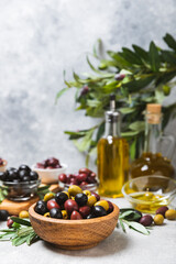 Set of green, red and black olives on a blue background. Different types of olives in bowls and olive oil with fresh olive leaves. Delicacy.Mediterranean Kitchen. Copy space.