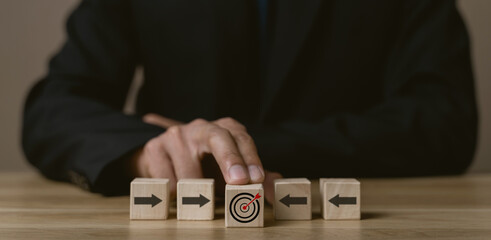 Business strategy. Businessman pointing wooden cube with target board icon and arrow on wooden...