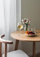 A glass of white wine, a plate of fruit on a wooden table in a cozy living room