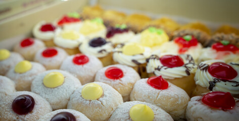 Round donuts stuffed with cream, chocolate and raspberry jam on the shelf in the delicious donut shop. copy space