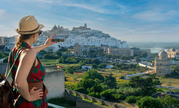 Young elegant  tourist taking photos with her smartphone in Ostuni, the white city  in the south of italy