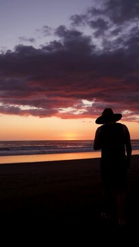 traveler on Tamarindo Beach watching the orange and purple sunset meditating, taking pictures and enjoying the sound of the sea and the warmth of the sunset in Guanacaste, Costa Rica.