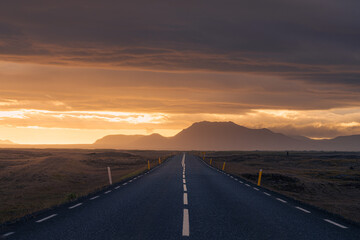 Dramatic sunset over straight asphalt road in Iceland