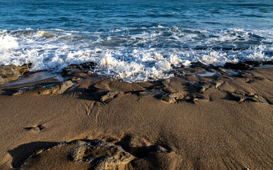 small waves crashing on the rocks at the edge of the sea.