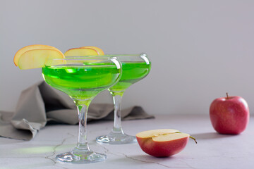 Homemade green apple martini cocktail with apple pieces in glasses