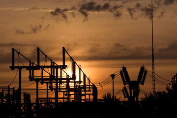 Sylwetki elementów stacji elektroenergetycznej na tle słońca