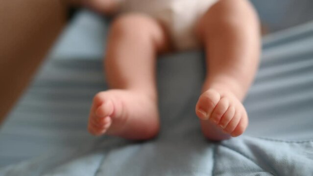Close-up of a newborn baby's feet and toes. A cute baby is playing in a child seat. Protection of childhood, motherhood.