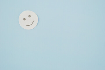 Smiley from white paper on blue background. World Day of Peace. Day Against Humiliation. International Day Of Human Fraternity. International Day of Living Together in Peace
