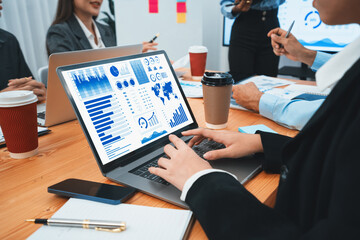 Multiracial analyst team use BI Fintech software to analyze financial data on meeting table. Financial dashboard data display on laptop screen with analyzed chart for marketing indication. Concord