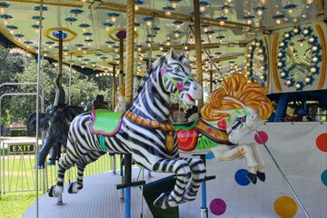 Zebra, horse, and elephant on a carousel ride in the park.