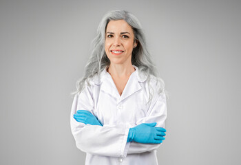 Confident Doctor Woman Posing Wearing White Coat On Gray Background