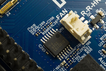 Close up of a PCB with a chip ant components like capacitors and resistors.