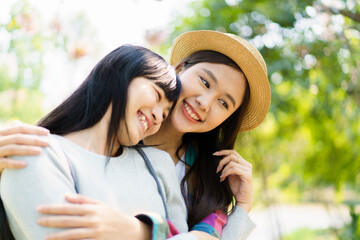 Happy cheerful Asian lovely female couple or LGBT couple hugging together and smiling to camera. 
