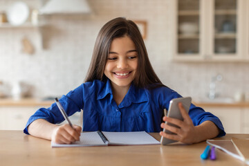 Girl Doing Schoolwork On Smartphone Taking Notes Sitting At Home