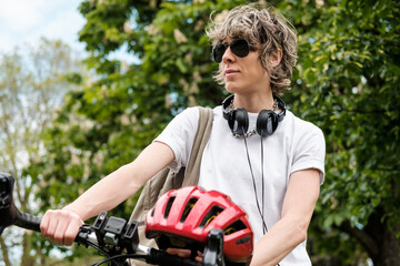 Naklejka premium Portrait of non-binary person holding a bike and a helmet.