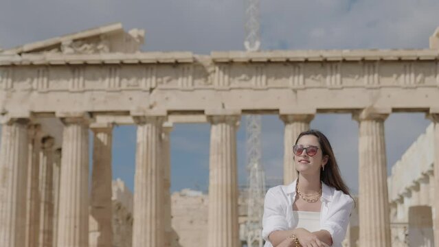 A tourist woman on summer vacations sits and relax near the Parthenon Temple at the Acropolis of Athens, Greece
