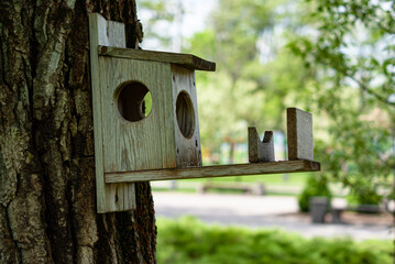 A wooden birdhouse hangs on a tree. A house for birds. Homemade birdhouse.