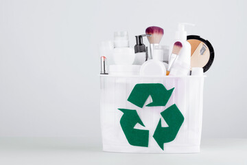  A container full of cosmetic products with a recycling sign on a gray background. Waste segregation, waste sorting, waste recycle. Environmental protection and sustainability concept. 