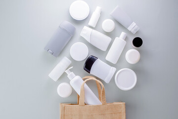 Beauty products spilled from a bag on a gray background. Buy and consume less cosmetics....