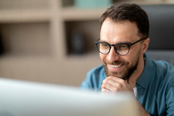 Closeup Of Smiling Handsome Man In Eyeglasses Working With Laptop In Office