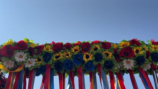 Ukrainian ethnic wreaths with flowers and colorful ribbons against blue sky.