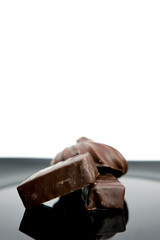 chocolates on a black plate white background space for text vertically delicious sweets instead of advertising Cubes of milk chocolate bar isolated on white background. High quality
