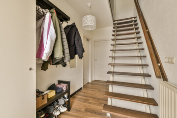a room with some clothes hanging on the wall and stairs leading up to the second floor in an attic...