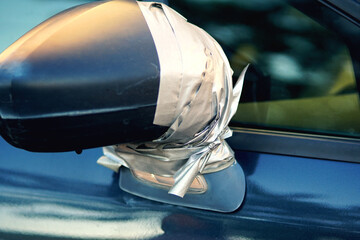 The damaged side mirror of the car was repaired with metallic-colored adhesive tape