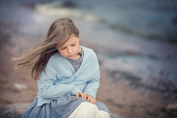 Girl on the beach and seagulls flying around on cloudy day